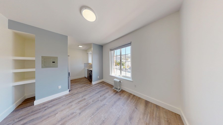 A room with a window and a wooden floor.